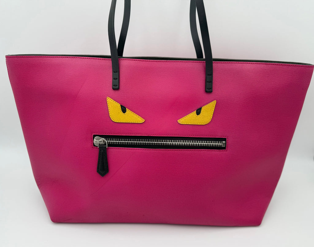 Pink tote bag with yellow eyes and a black zipper on a white background