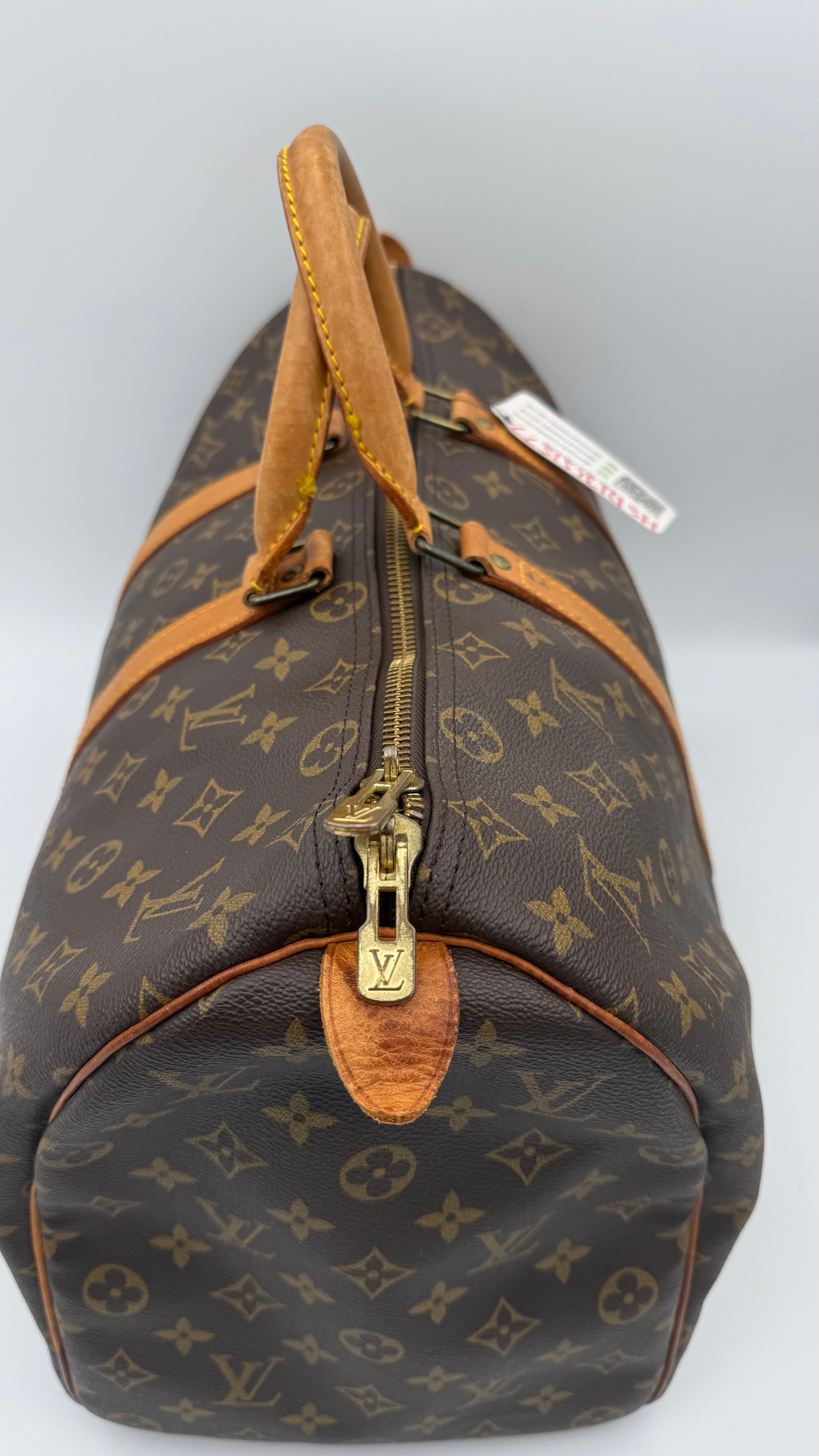 Brown monogram duffel bag with gold zipper on a white background