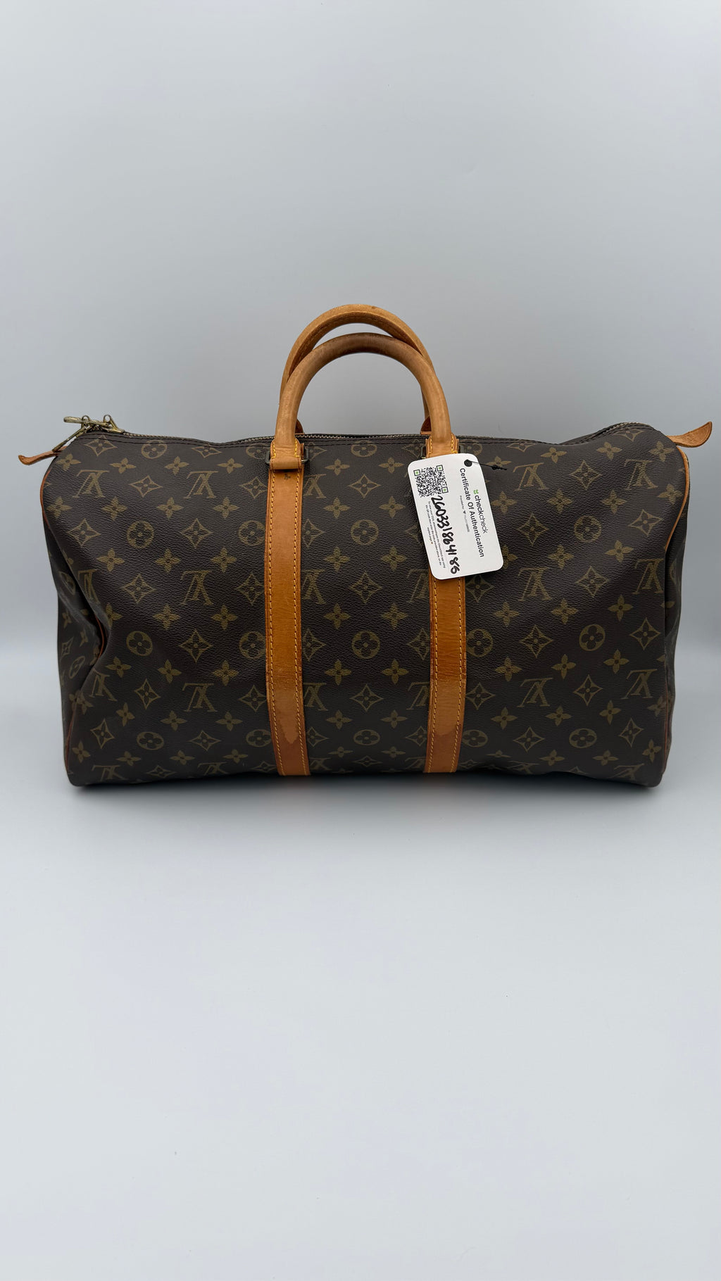 Louis Vuitton monogram duffel bag with a visible tag on a gray background