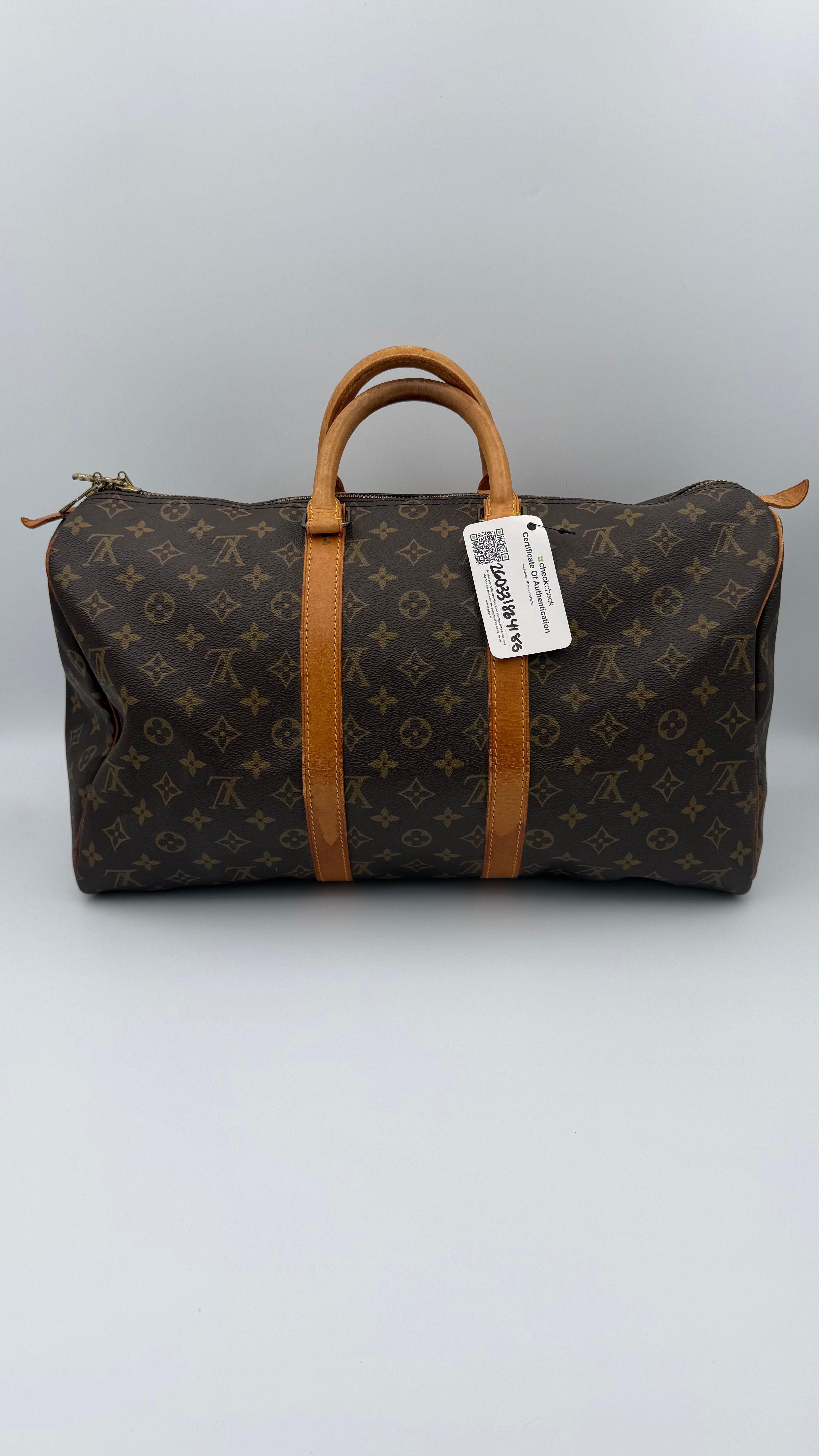 Louis Vuitton monogram duffel bag with a visible tag on a gray background