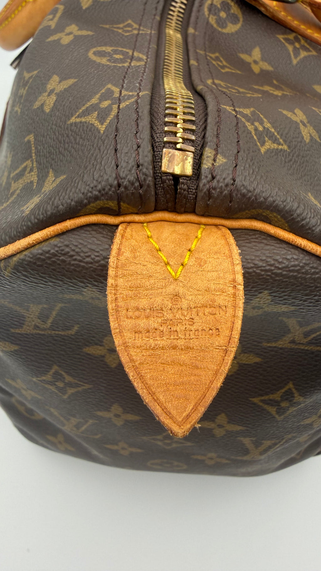 Close-up of a Louis Vuitton monogram duffel bag with a patch on a white background